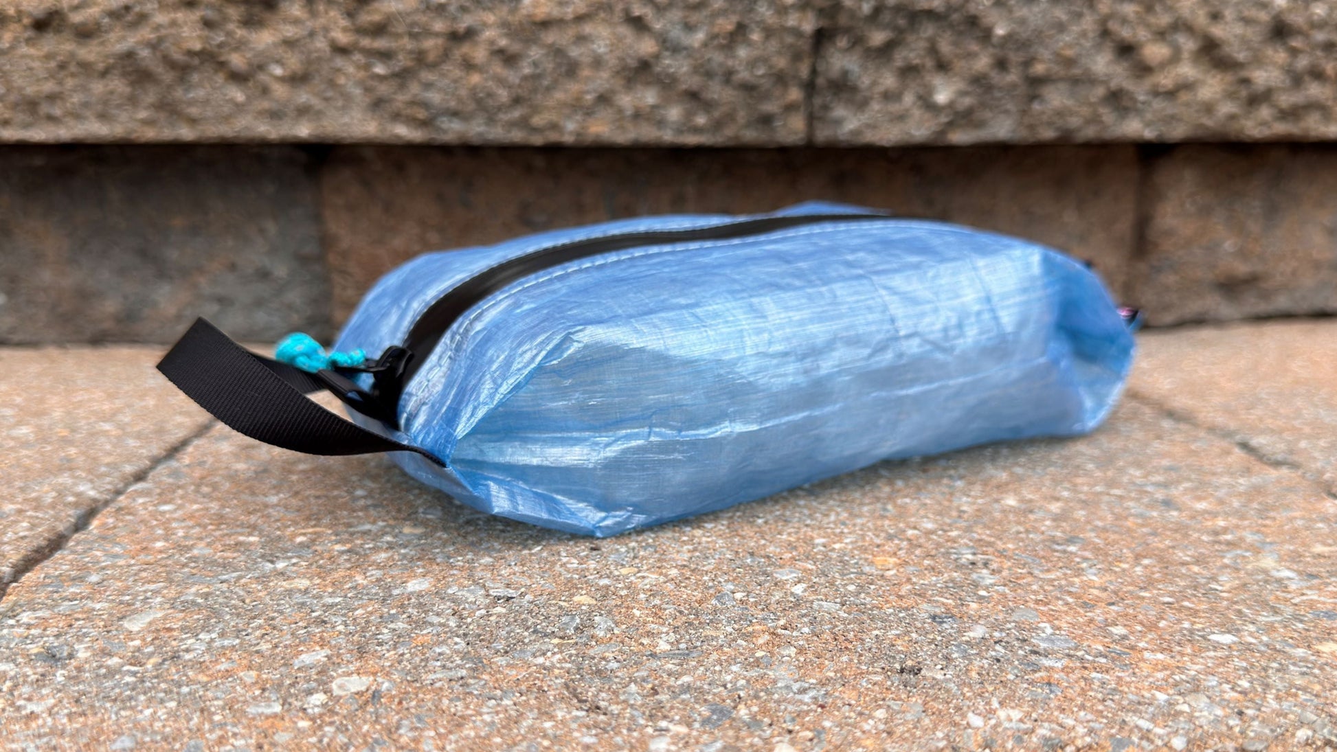 Blue plastic bag with a black zipper on a stone surface